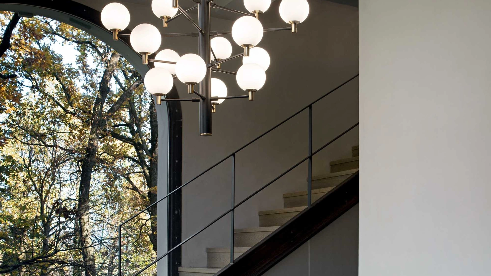 Lampada a sospensione Copernico in metallo verniciato nero opaco con dettagli in ottone e diffusori in vetro incamiciato bianco soffiato e acidato di Ideal Lux